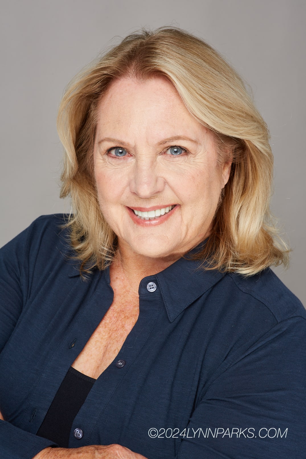 Cookie Colletti actor headshot wearing navy shirt and smiling