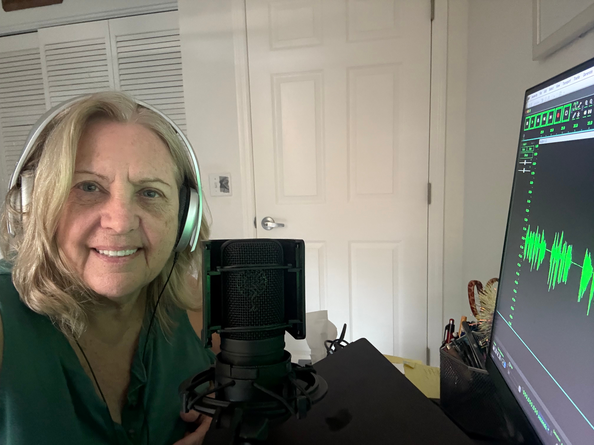 Cookie Colletti recording voice over in home studio with microphone and audio waveform